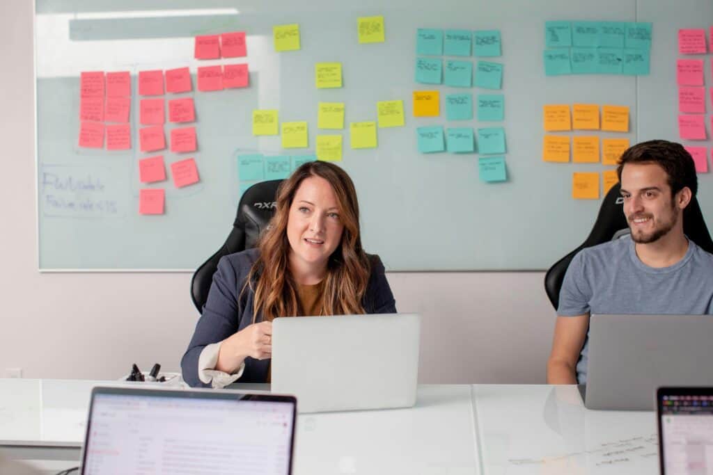 A business meeting with coloured post-it notes on the whiteboard behind