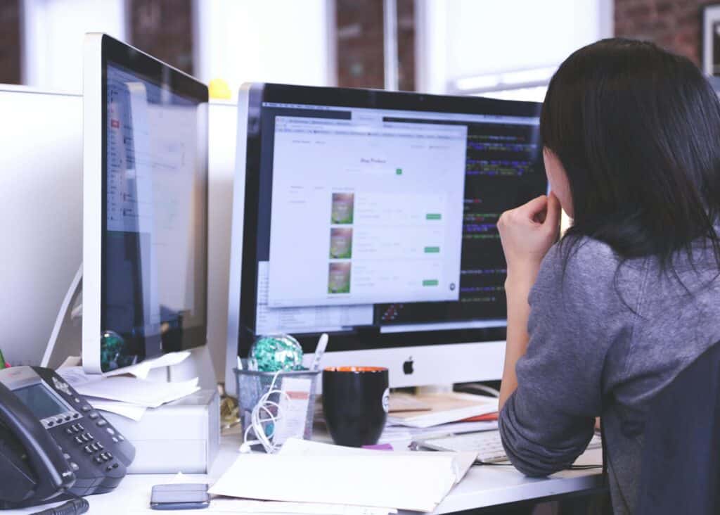 Someone looking at two large monitors