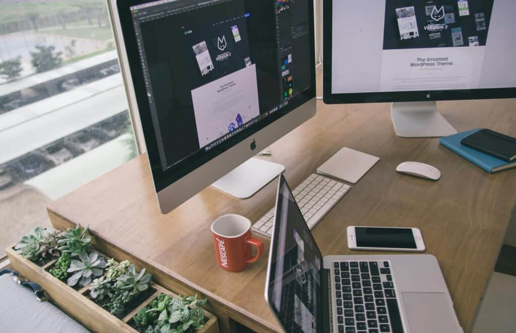 Two large monitors and a laptop on a desk, next to a phone