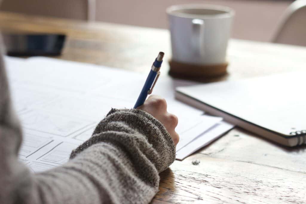 Someone writing on a notepad with a pen